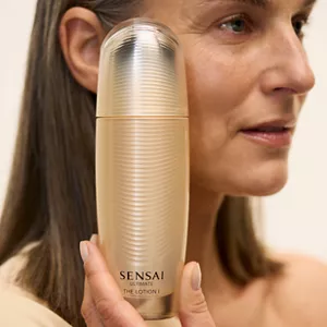 Close up of person holding Ultimate The Lotion 1 next to their face with their hand in neutra setting